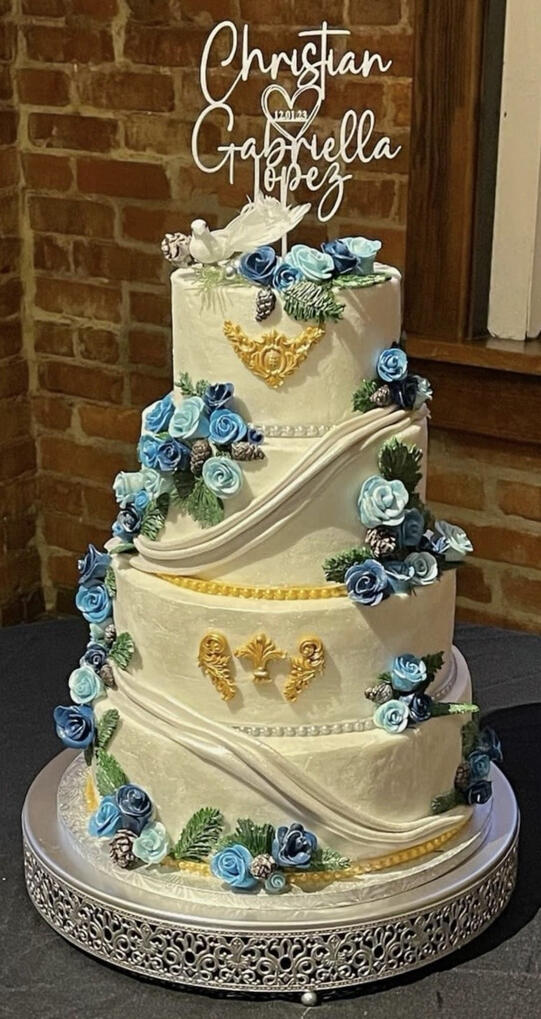 Elegant Blue & Gold Wedding Cake Elegant tiered wedding cake decorated with handcrafted blue roses, gold accents, and ornate detailing.