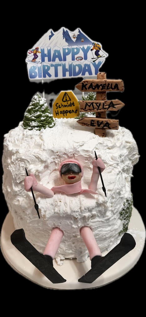 Custom Ski-Themed Cake White buttercream ski-themed cake with a handcrafted fondant skier, snowy mountain details, and personalized fondant trail signs.
